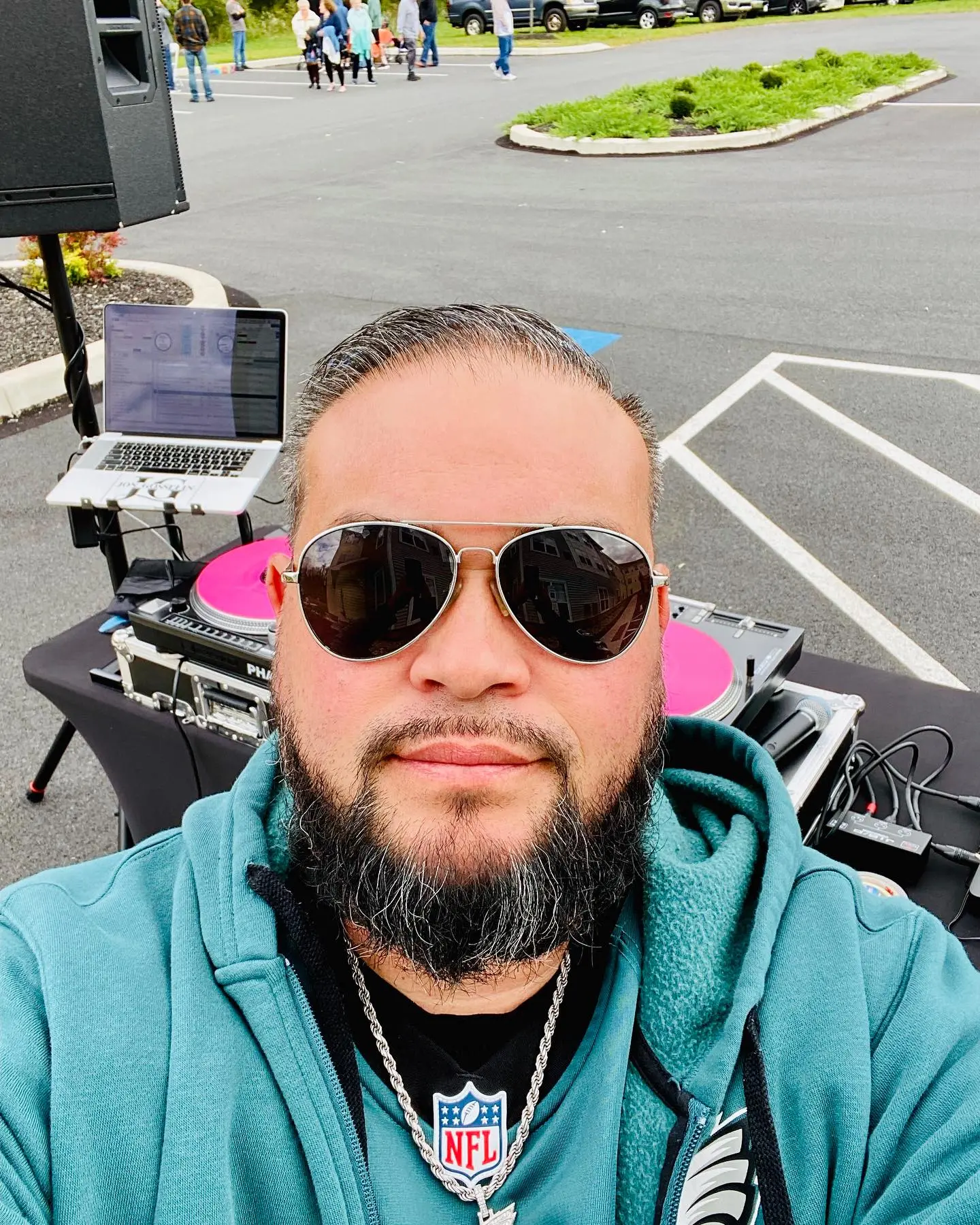 Jon Gosselin wearing sunglasses and a hoodie, posing outdoors with DJ equipment in the background.