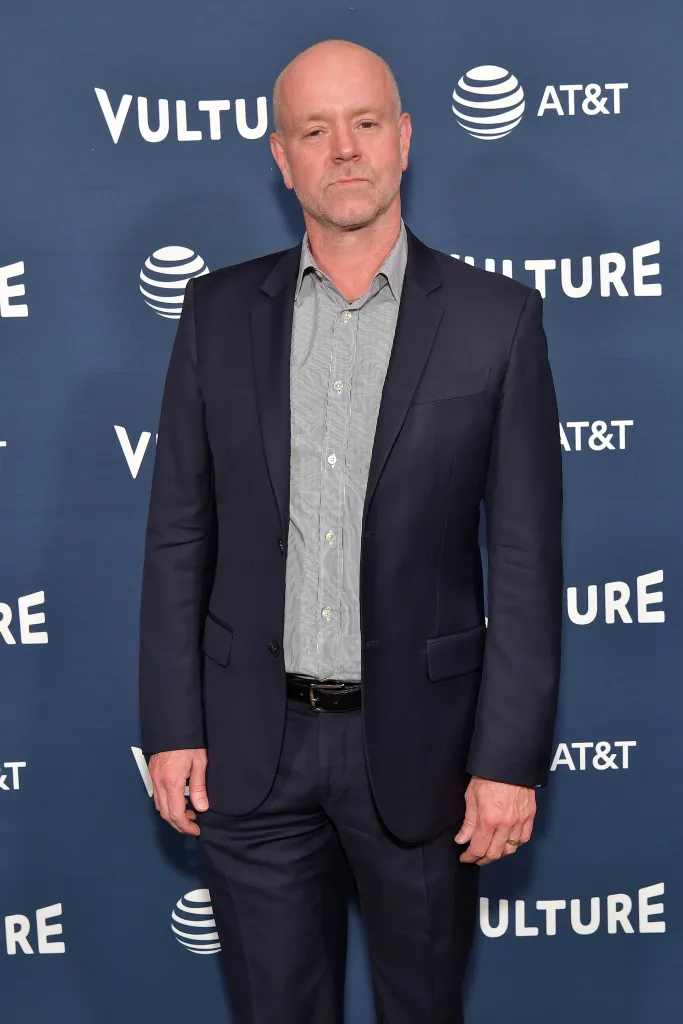 Jonathan Van Meter wearing a dark suit and striped shirt in front of a blue backdrop.