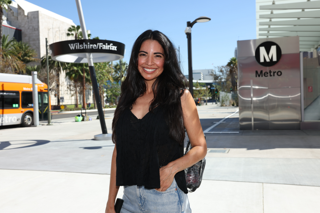 Juiana stands smiling at the Wilshire/Fairfax Metro station in Los Angeles.