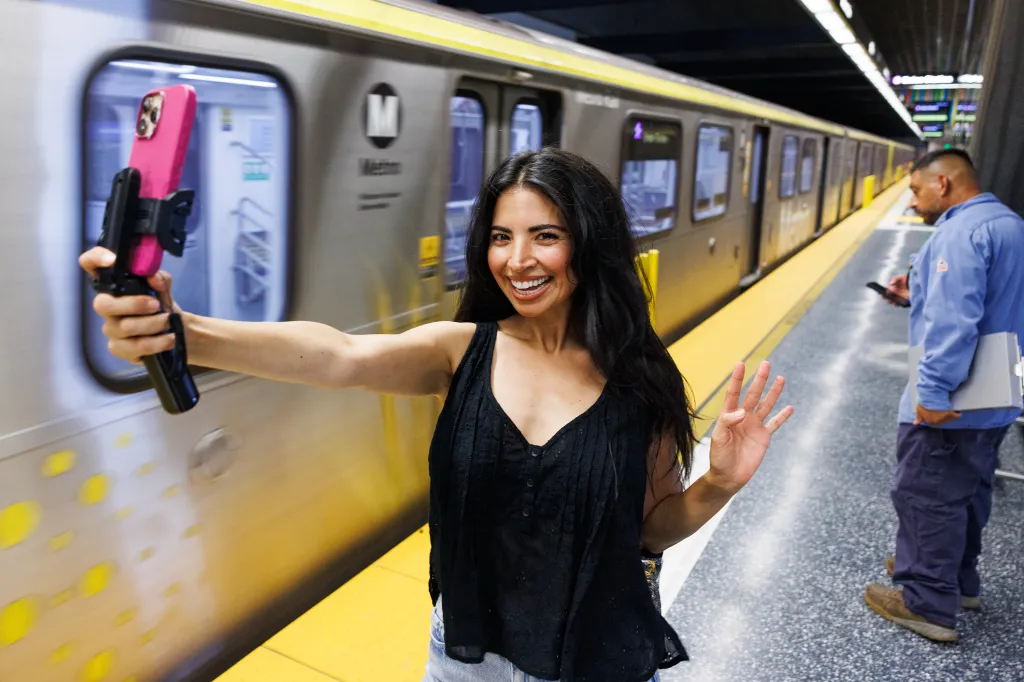 Juiana takes a selfie in front of a subway train at the Wilshire Blvd and Fairfax Ave station in Los Angeles, California.