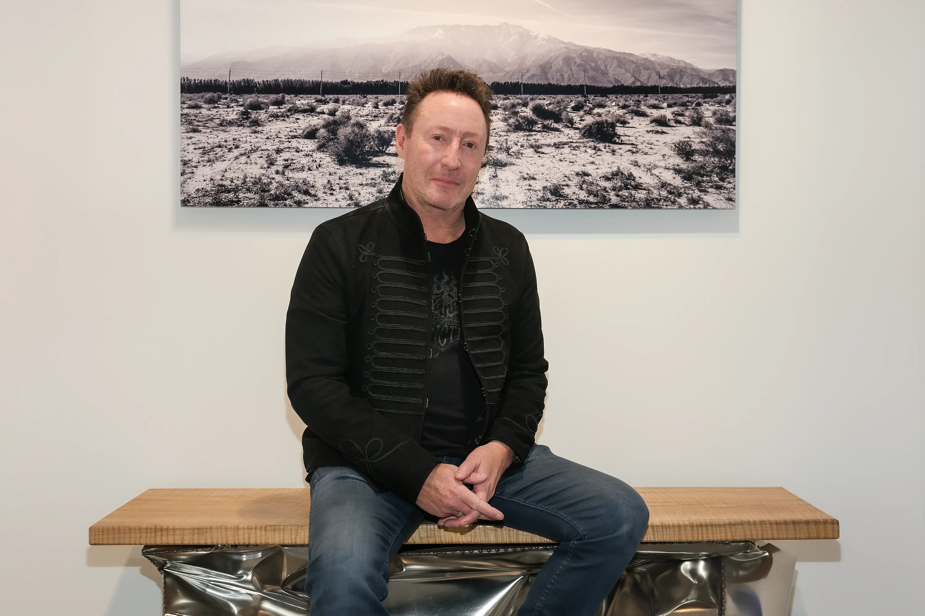 Julian Lennon sitting in front of one of his photographs at the opening reception of his exhibition 