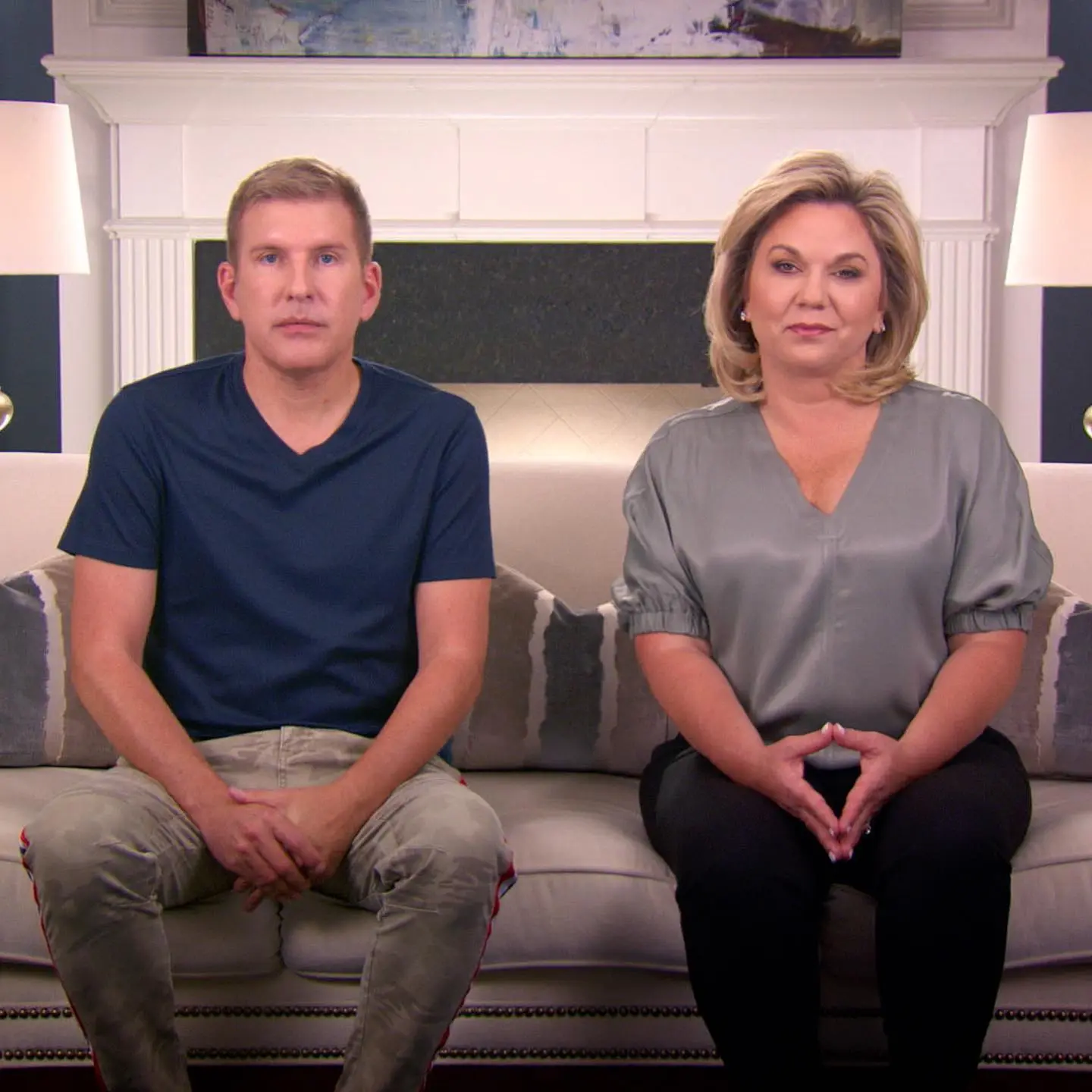Todd Chrisley and Julie Chrisley sitting side by side on a couch in a living room.