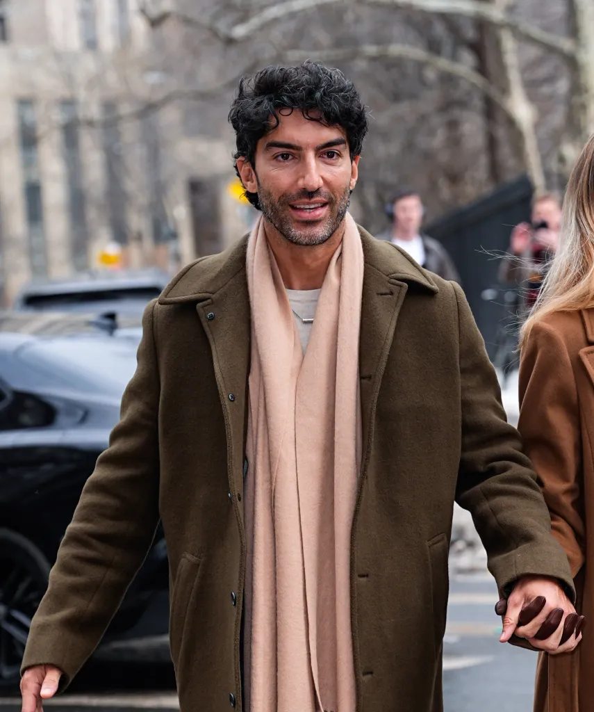 Justin Baldoni wearing an olive coat and beige scarf in New York City.