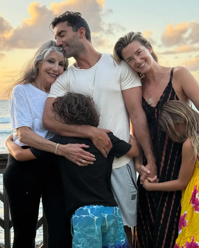 Justin Baldoni embraces his family in a group hug outdoors at sunset.