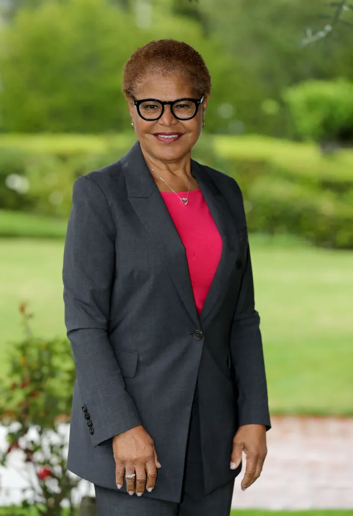 Karen Bass wearing a grey suit jacket and glasses outdoors.