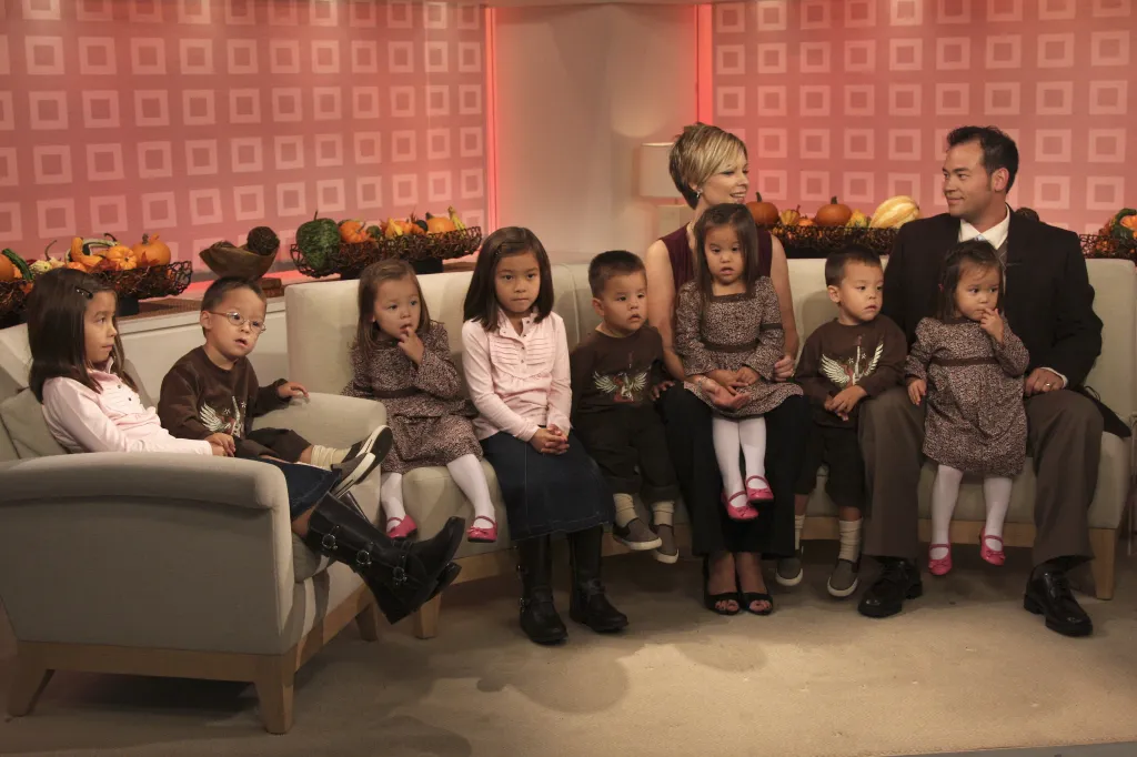Kate and Jon Gosselin sit on a couch with their twin daughters and sextuplets.