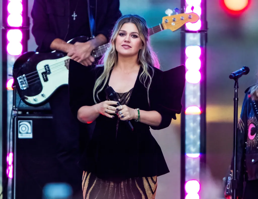 Kelly Clarkson performs on the Today show with a band in the background.