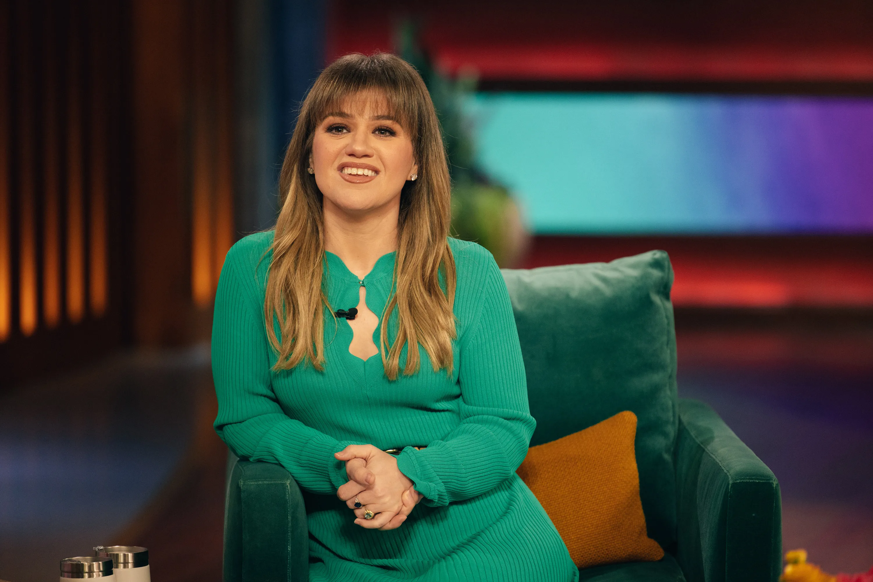 Kelly Clarkson sitting on a talk show set.
