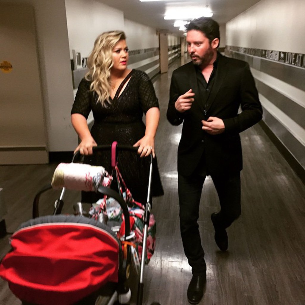 Kelly Clarkson and Brandon Blackstock walking down a hallway, with Clarkson pushing a stroller.