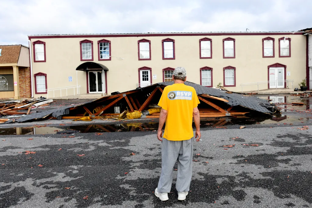 Kenny Smith looks at an apartment roof that was torn off and landed in front of his apartment in East Milton, Fla.