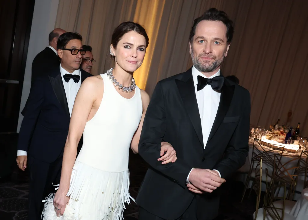 Keri Russell and Matthew Rhys attending an awards show, with Russell in a white fringe dress and Rhys in a tuxedo.