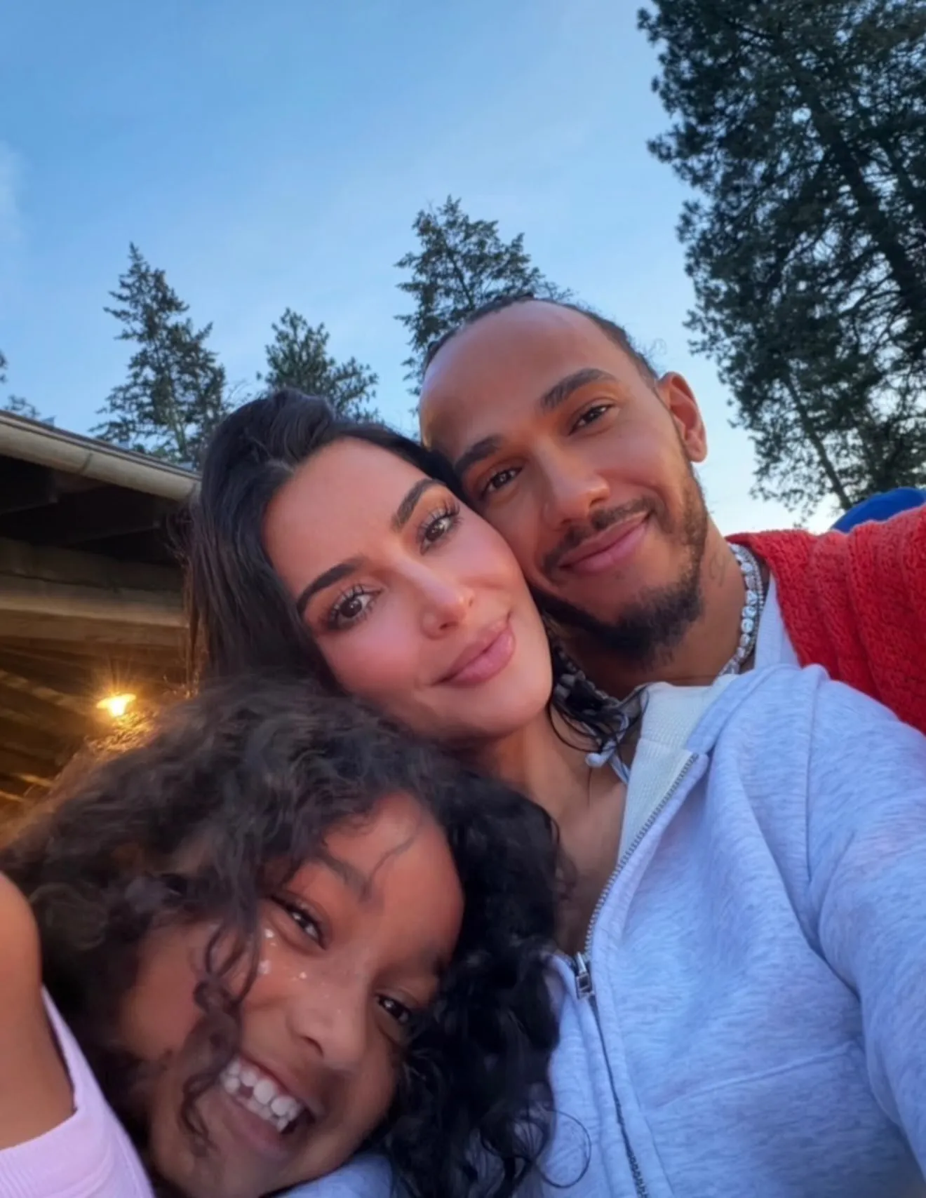 Kim Kardashian and Lewis Hamilton take a selfie together with one of her kids outside.