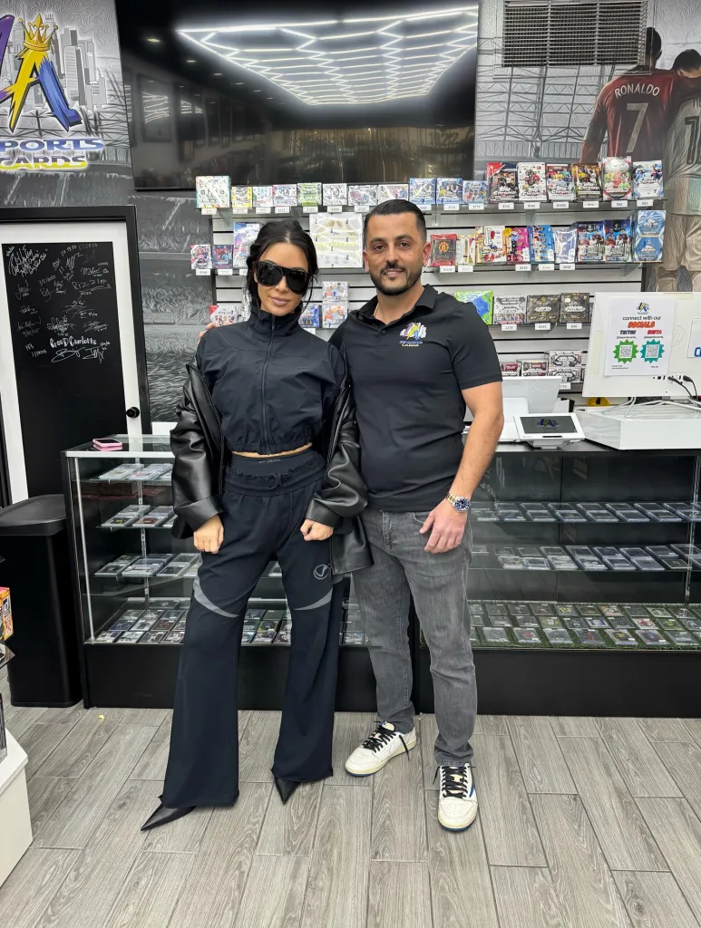 Kim Kardashian standing next to a store owner inside a sports card shop.