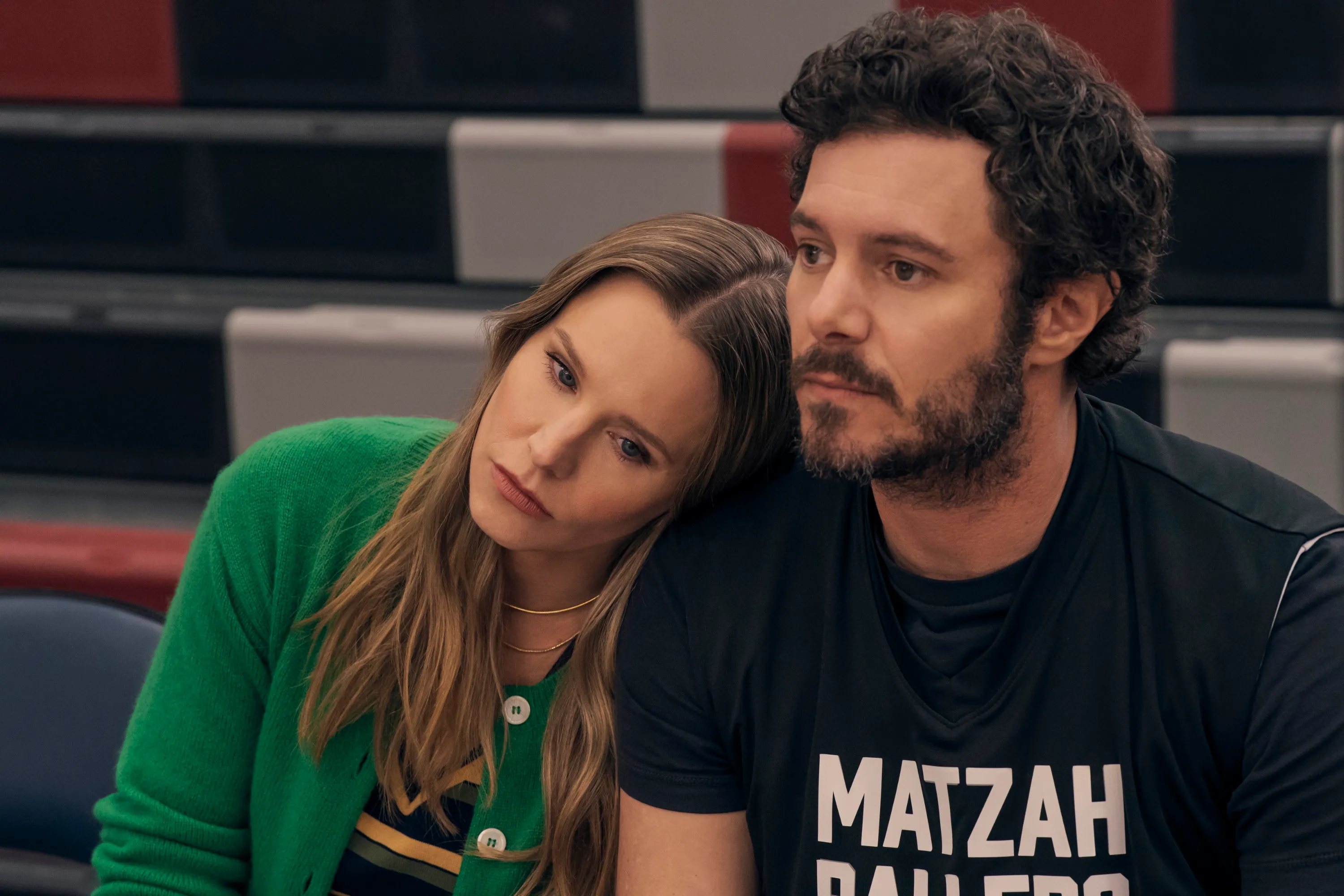 Kristen Bell leans her head on Adam Brody's shoulder while sitting in bleachers in Nobody Wants This.