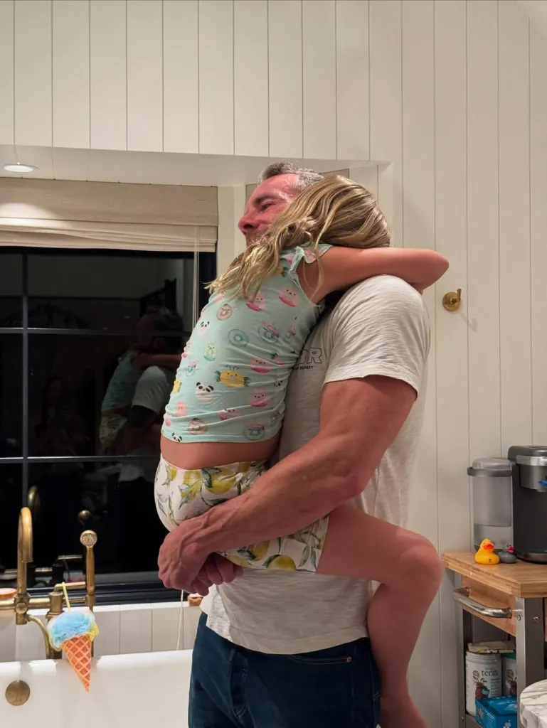 Dax Shepard holding and hugging one of his daughters.