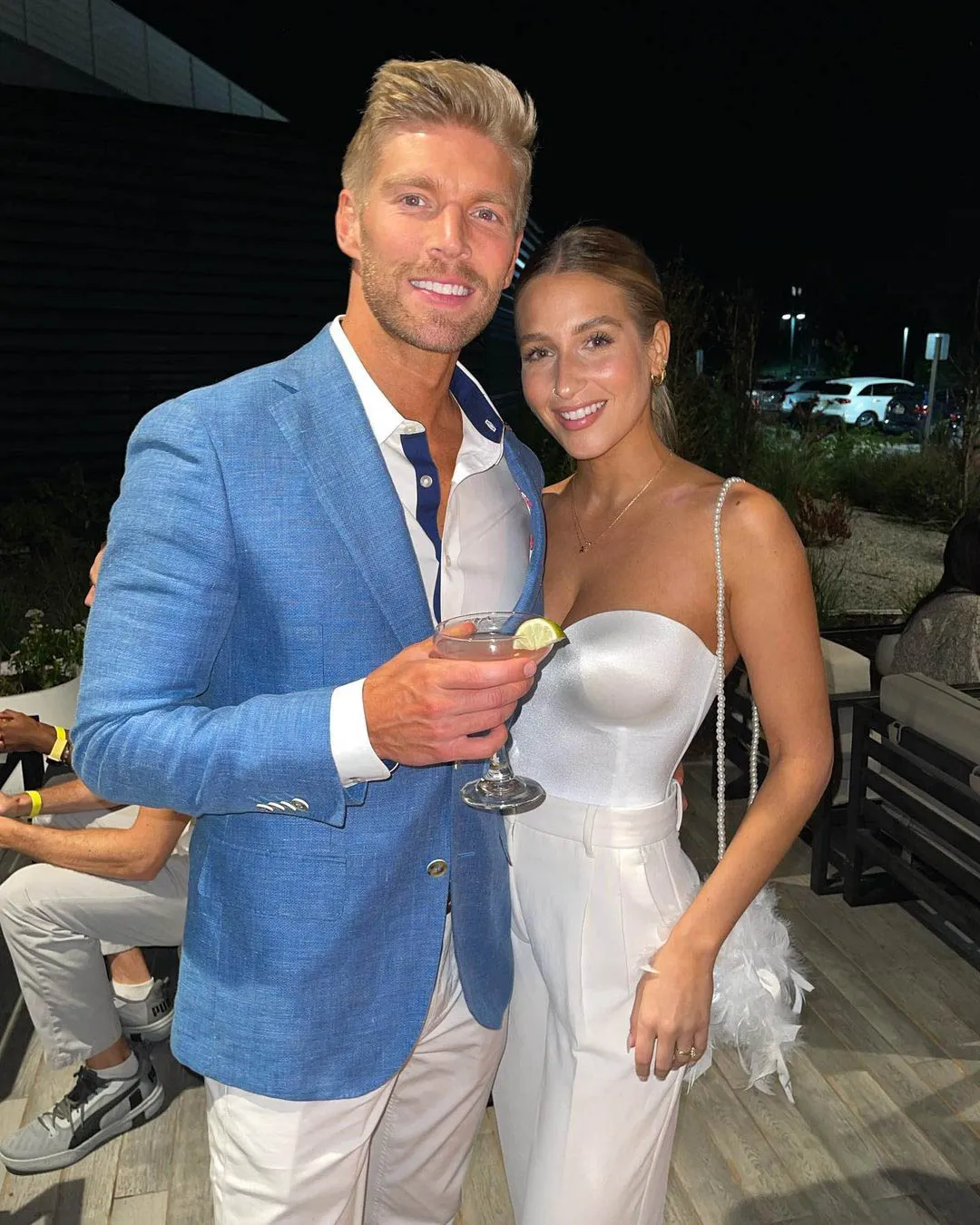 Kyle Cooke and Amanda Batula posing together outdoors at night.