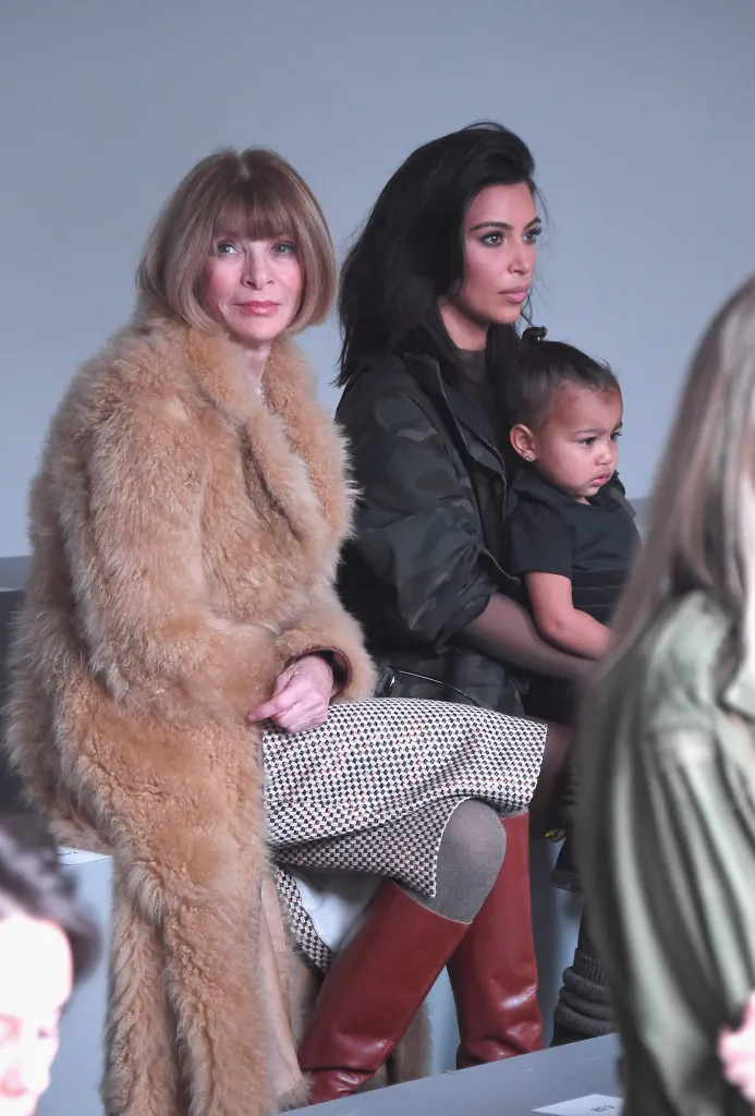 Anna Wintour, Kim Kardashian, and North West sitting in the front row of a fashion show.