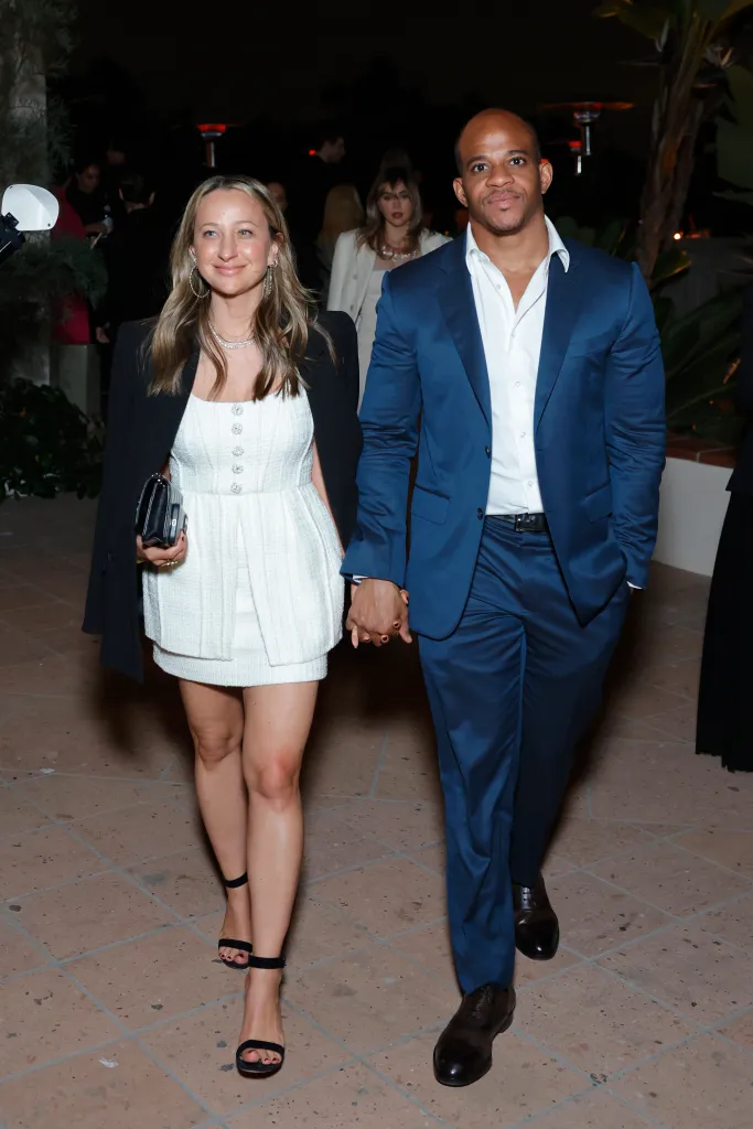Jennifer Meyer and Geoffrey Ogunlesi holding hands at an event.
