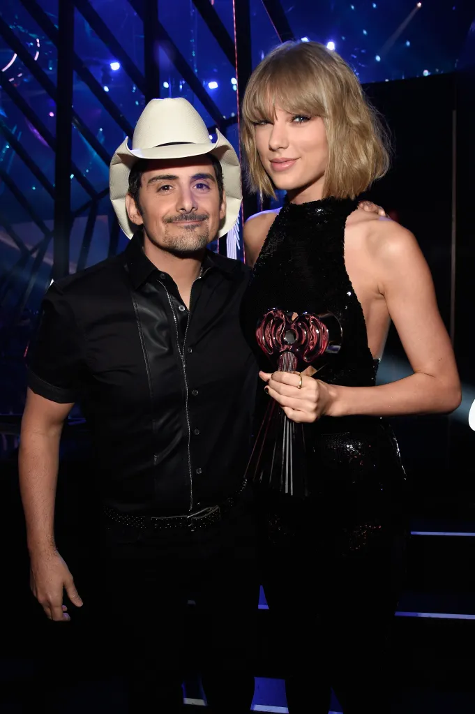 Singers Brad Paisley and Taylor Swift pose backstage, with Swift holding an award.
