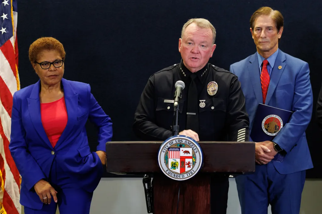 LAPD Police Chief Jim McDonnell speaks at a press conference flanked by two officials.
