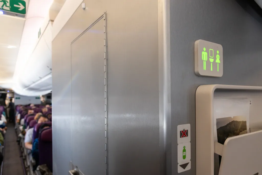 An airplane lavatory sign illuminated in green, indicating that the restroom is unoccupied and available.