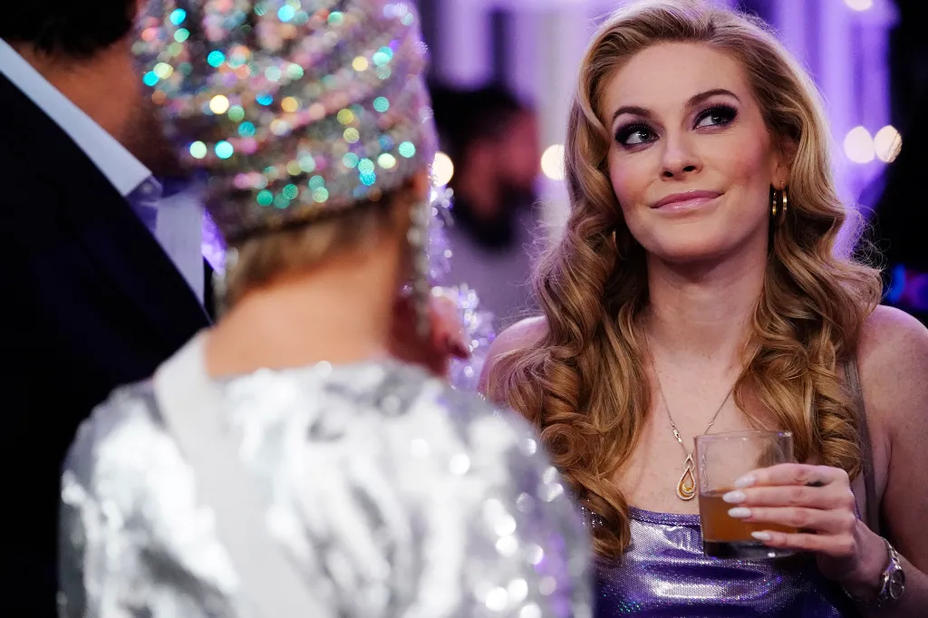 Leah McSweeney holding a drink while looking at someone wearing a sequined outfit.