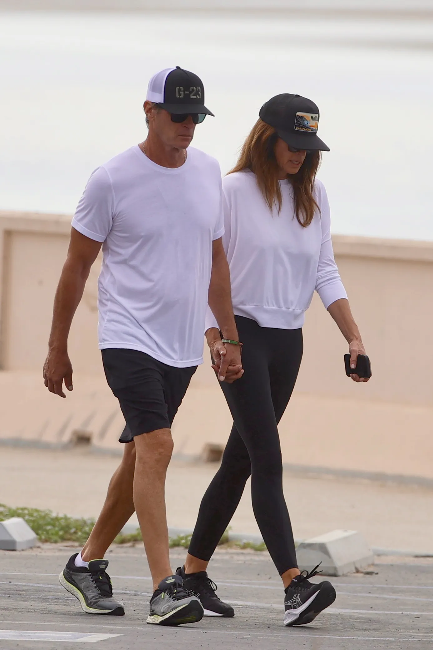 Cindy Crawford and Rande Gerber holding hands while walking in Zuma Beach.