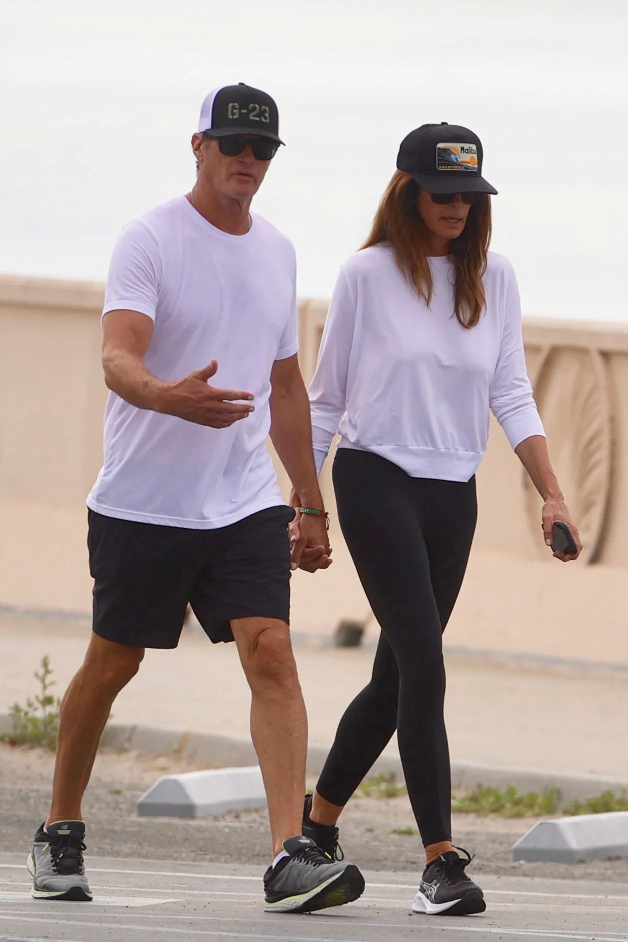 Cindy Crawford and Rande Gerber walking together hand-in-hand at Zuma Beach.