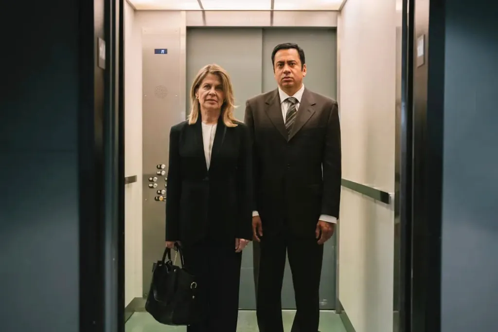 Linda Hamilton as Ellyn Garofalok in a black suit and white top, and Kal Penn, in a black suit, as Dr. Sandeep Kapoor in Trust Me, I'm a Doctor.