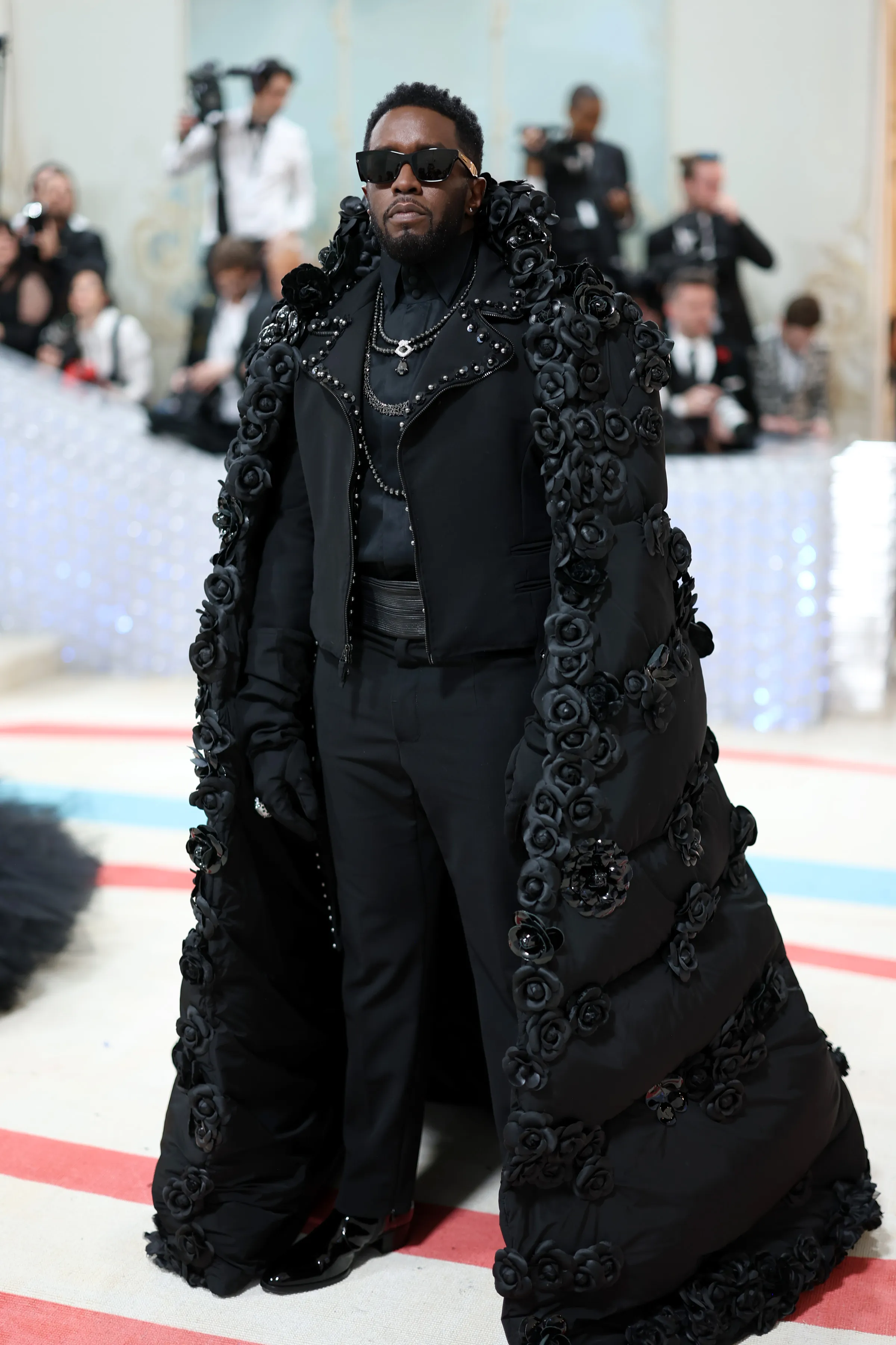 Sean 'Diddy' Combs wearing a black outfit and a cape decorated with black roses at the Met Gala.