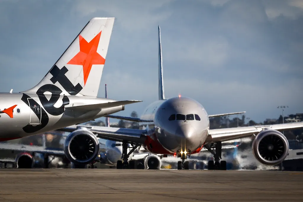 A Jetstar Airlines plane lines up with other aircraft on a runway at Sydney International Airport.