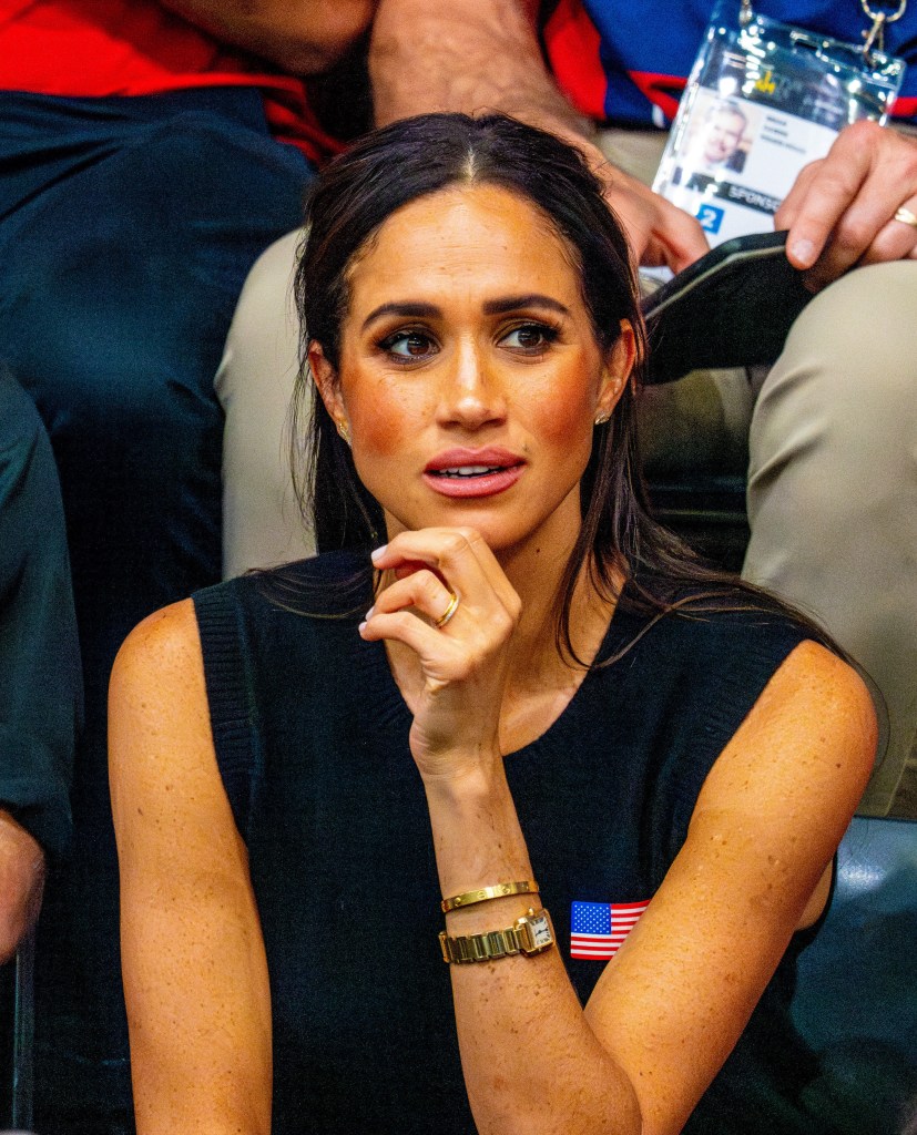 Meghan Markle seated in the audience with her hand near her chin.