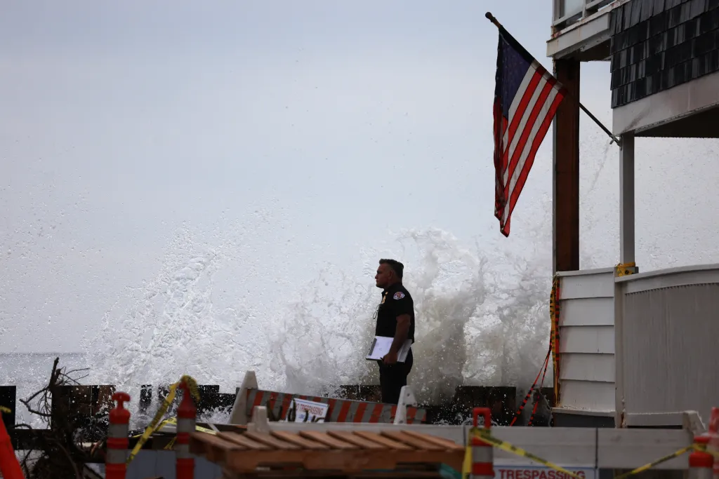 A Long Beach Fire Department officer watches as waves pound the boardwalk in Long Beach, California.
