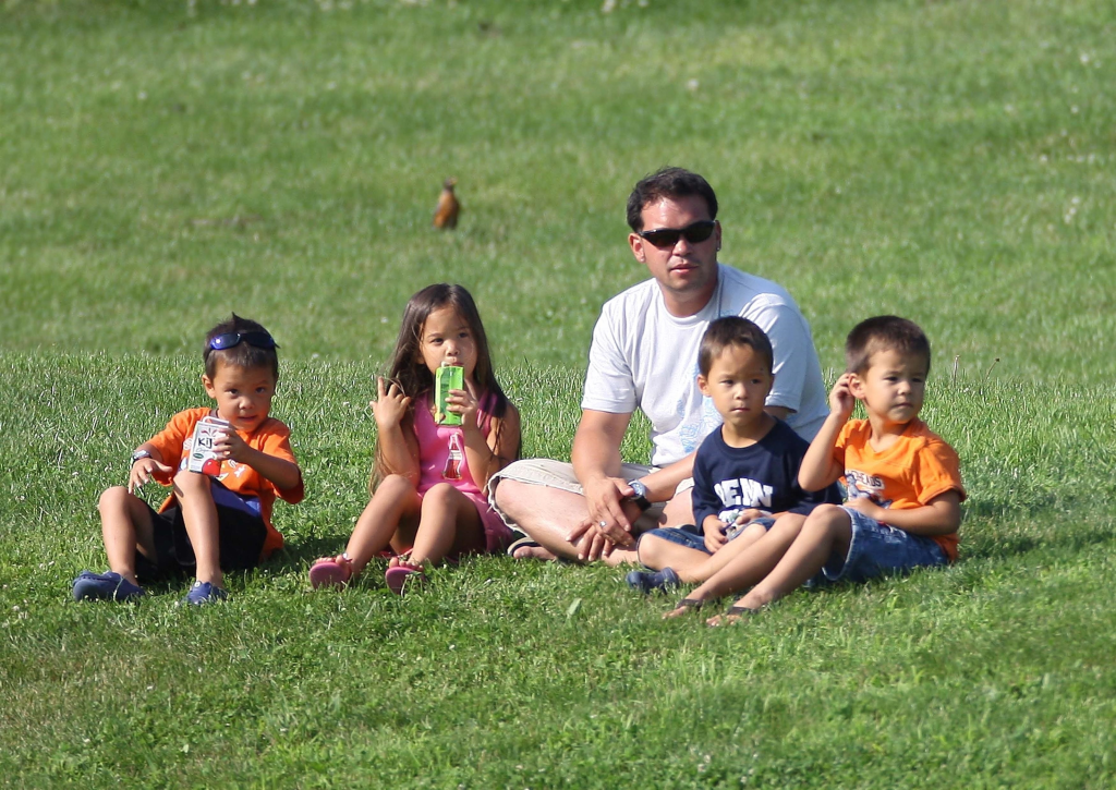 Jon Gosselin sitting on the grass with four children.