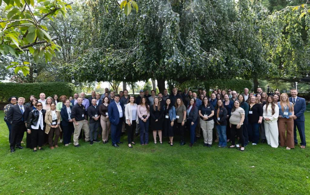 Group portrait of professionals and law enforcement personnel involved in the Long Island Missing Child Rescue Operation, standing outdoors beneath a large tree.