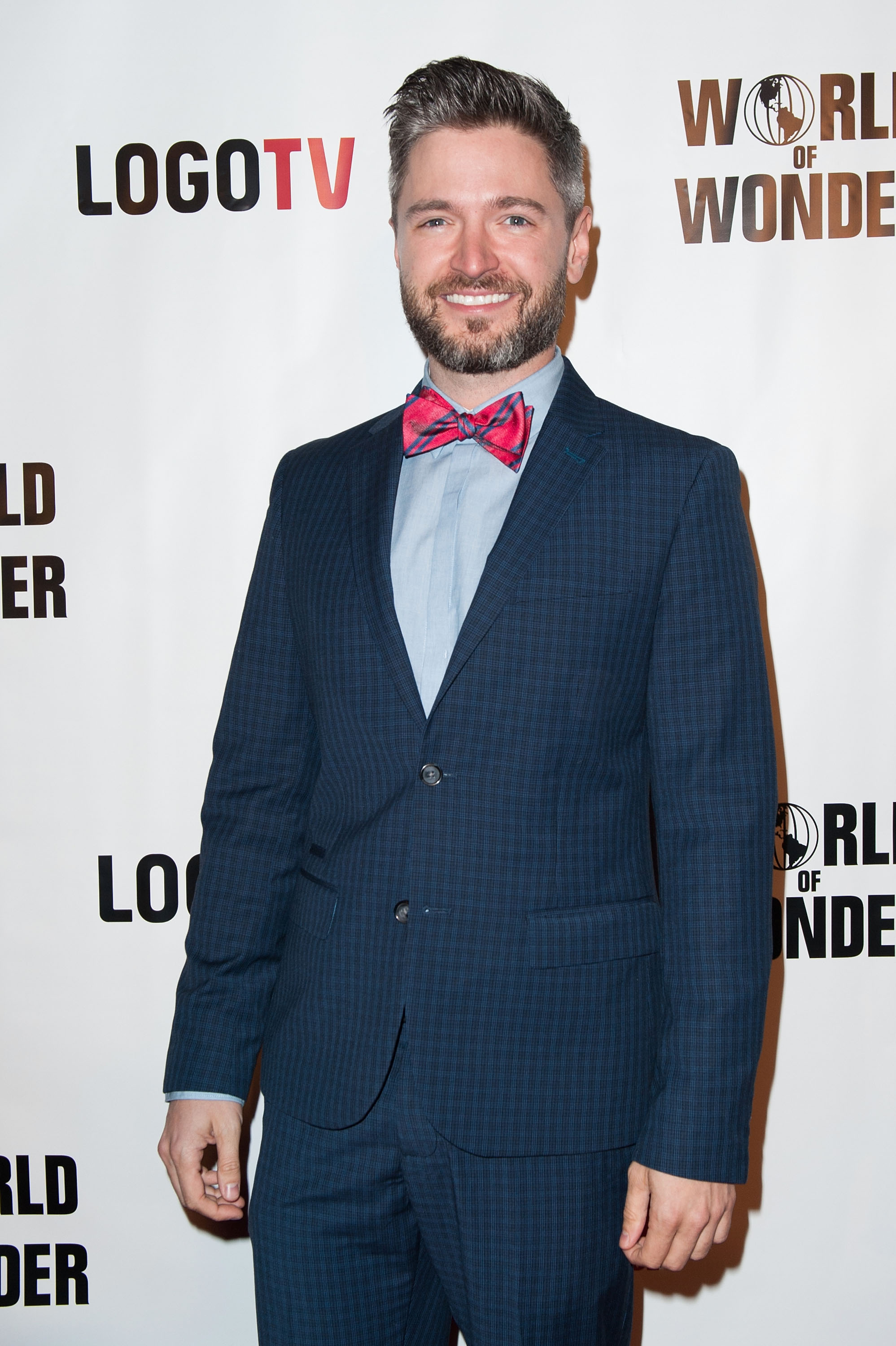 Lucian Piane poses in a blue suit and red bowtie at the premiere of Logo TV's 