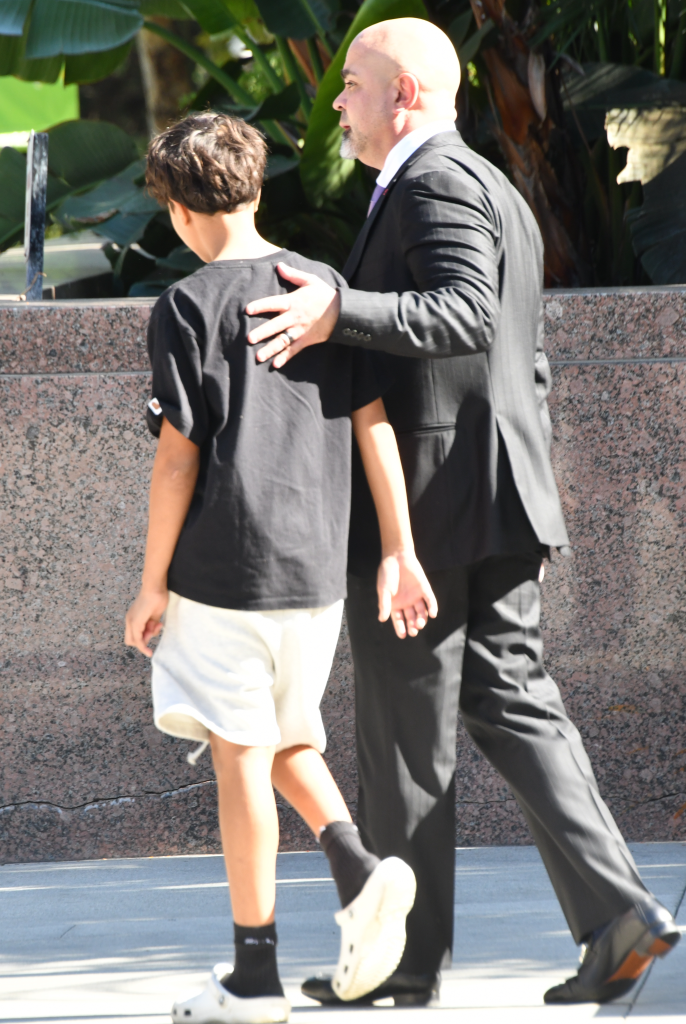 Maceo Martinez walking with a man in a suit outside a courthouse.