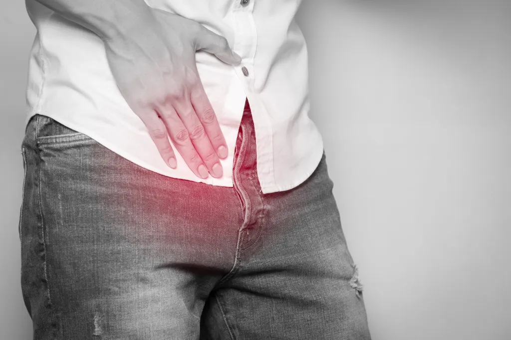 A man holding his crotch to illustrate prostate health awareness, with the painful area highlighted in red.