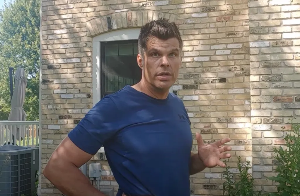 Matthew Arndt standing outside in front of a brick wall.