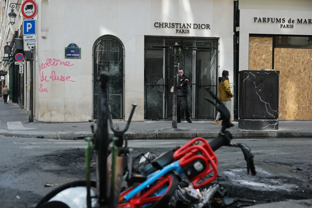 A man walks past a vandalized Christian Dior store in Paris following protests.
