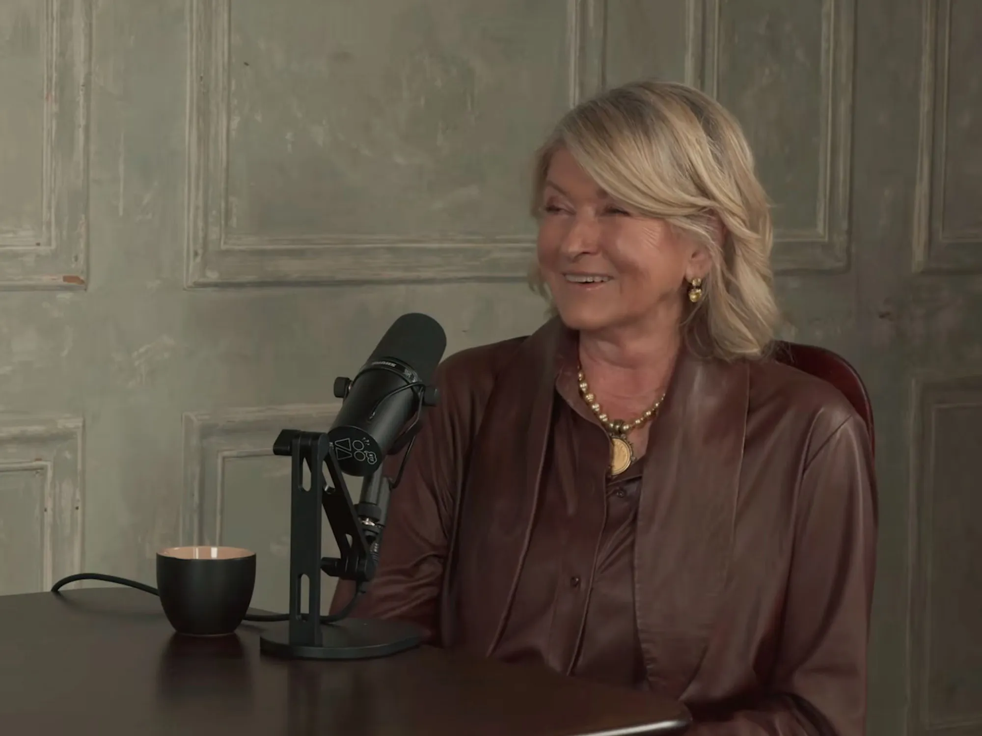 Martha Stewart sitting at a table with a microphone in front of her.