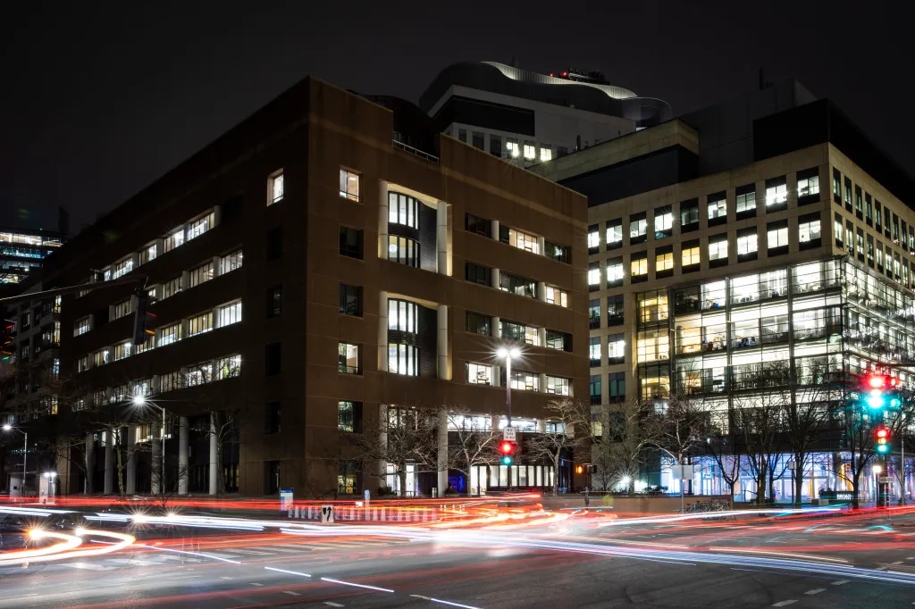 The Whitehead Institute at the Massachusetts Institute of Technology at night, with light trails from passing cars on the street.