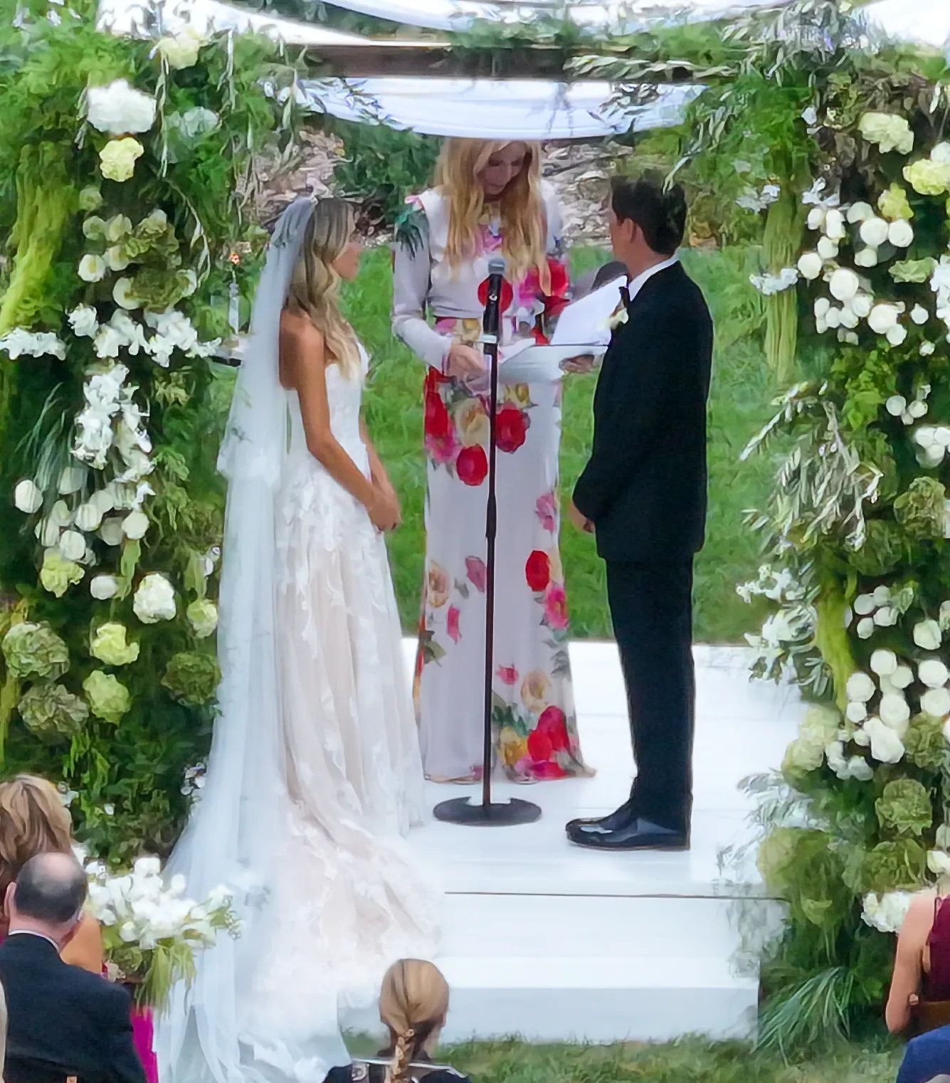 Matthew Lowe and Emily Markus at their wedding in Santa Barbara, California, officiated by Gwyneth Paltrow beneath a floral arch.