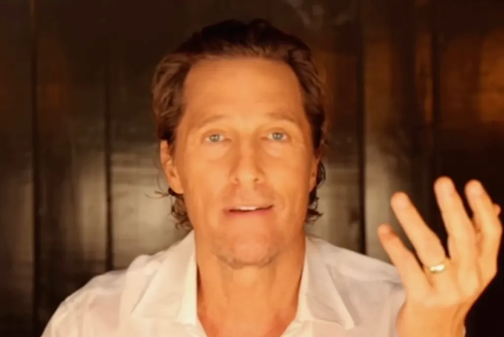 Matthew McConaughey speaking directly to the camera with his hand raised.