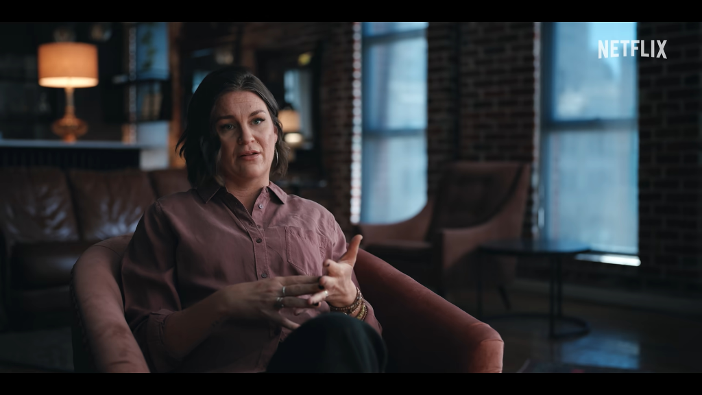 Matthew Perry's sister, Caitlin Morrison, being interviewed in a dimly lit room.