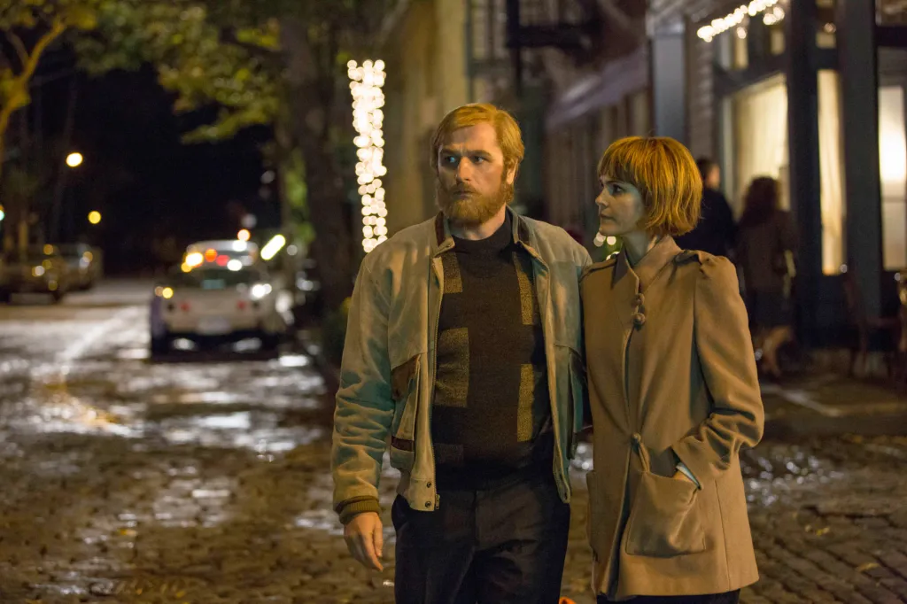 Matthew Rhys and Keri Russell walking together on a cobblestone street at night.