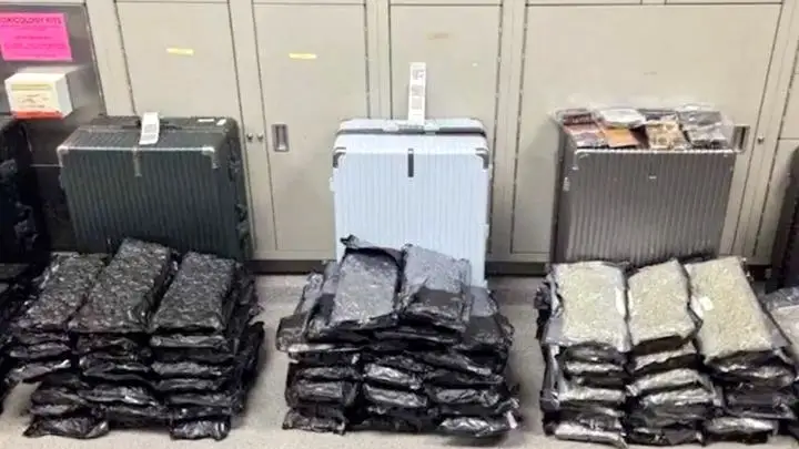 A drug haul found at Orlando International Airport, displayed as three suitcases with large stacks of packaged substances in front of them.