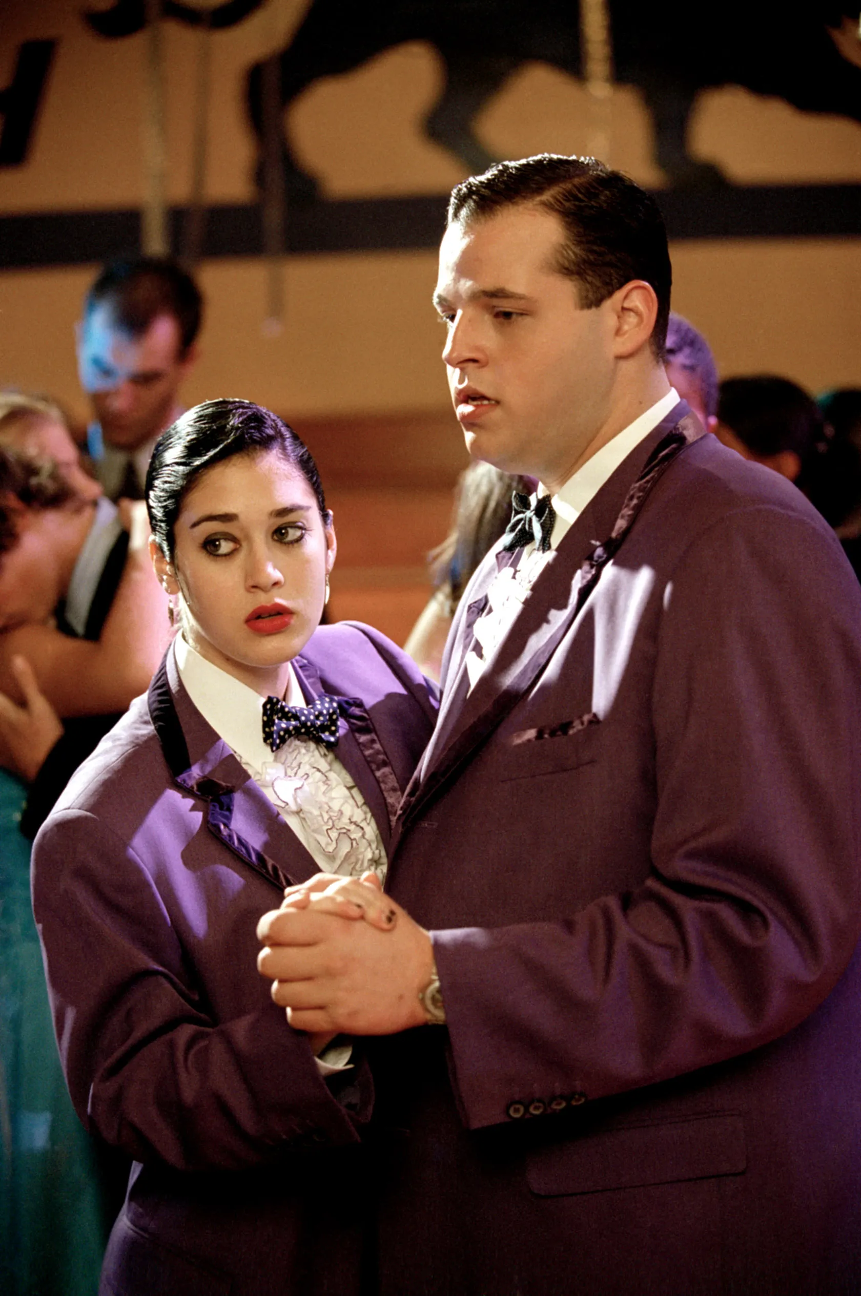 Lizzy Caplan and Daniel Franzese dancing in matching purple suits at a prom.