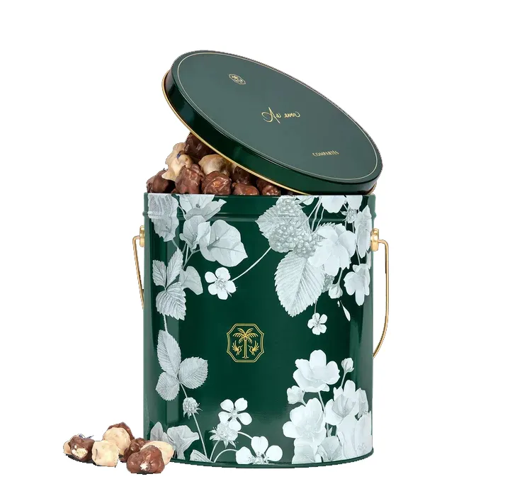 An As Ever collection dark green tin filled with chocolates, featuring a botanical white floral pattern and a gold handle.