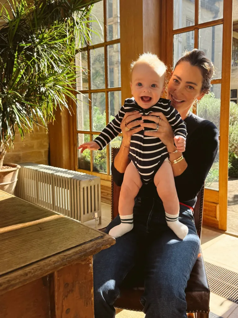 Meghan Markle, in a black top and blue jeans, holds's Kelly McKee Zajfen s baby, Jack, wearing a striped romper.